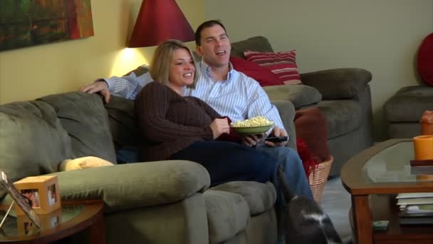 Пара смотрит телевизор, ест попкорн и дерётся за пульт. . — стоковое видео