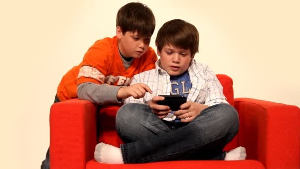 Два мальчика играют в портативную видеоигру . — стоковое видео