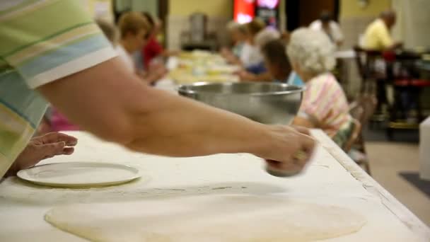 Seorang wanita menggunakan pemotong kue untuk memotong bentuk melingkar dalam adonan . — Stok Video