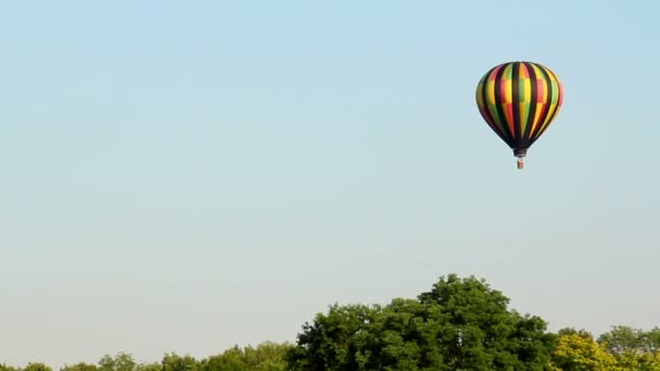 A hot air balloon gently glides through the air on a summer evening. — Stock Video