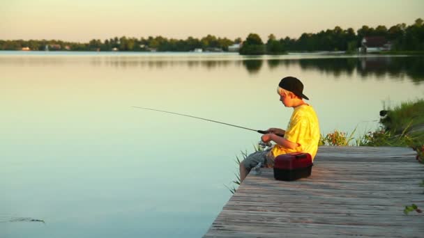 Un niño pesca temprano en la noche . — Vídeo de stock