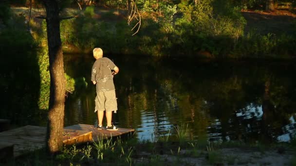 Un jeune garçon pêche en début de soirée . — Video