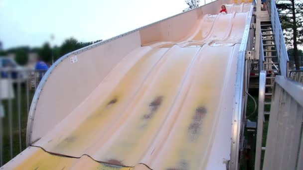 Une fille glisse sur une grande glissière lors d'un carnaval . — Video