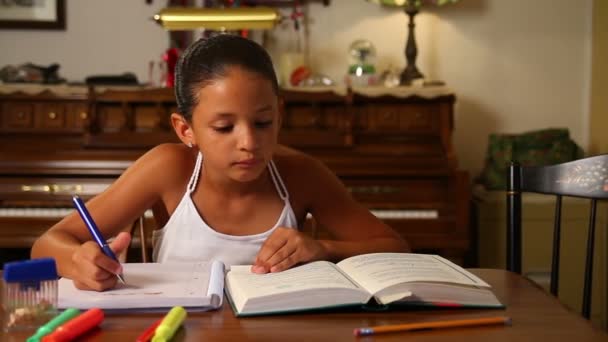 Молодая девушка самостоятельно делает уроки в столовой . — стоковое видео