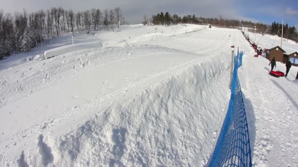 Riders slide down a snow tubing hill. — Stock Video