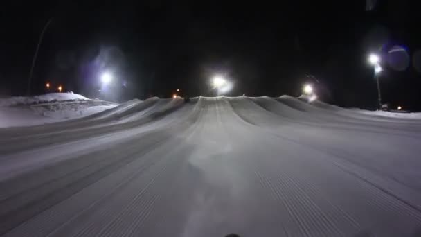 Rijden in een heuvel van de buizen sneeuw 's nachts. — Stockvideo