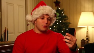 Noel Baba şapkası video içinde genç bir adam onun hareket eden smartphone üzerinde sohbet eder..