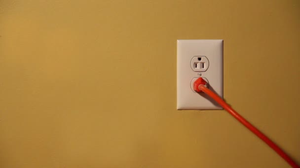 米国の壁のコンセントにオレンジの電気コードを差し込んで抜き男のクローズアップショット. — ストック動画