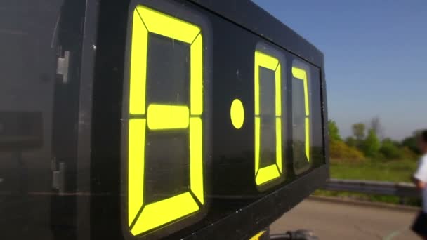 A race clock counts up as marathon participants run in the background. — Stock Video