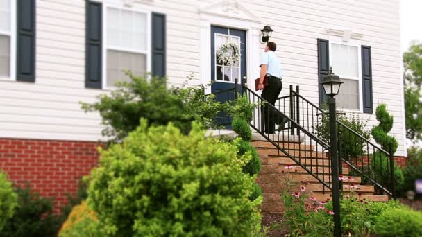 A door to door salesman walks up to a house and knocks on the door. — Stock Video