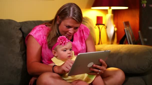 Una madre usa un tablet con il suo bambino sul divano . — Video Stock