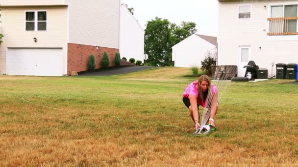 Une propriétaire déplace l'arroseur dans son jardin . — Video