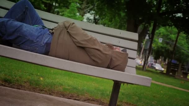Evsiz bir adam parkta bankta — Stok video