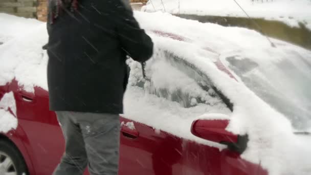 Человек убирает снег с машины — стоковое видео