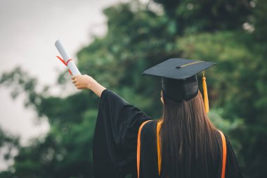 Elinde altın püsküllü mezuniyet şapkası olan üniversite mezunları, konsept eğitim mezunları üniversite mezunlarını kutluyor..