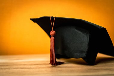 Siyah Mezuniyet Şapkası ahşap masa arkasına yerleştirildi