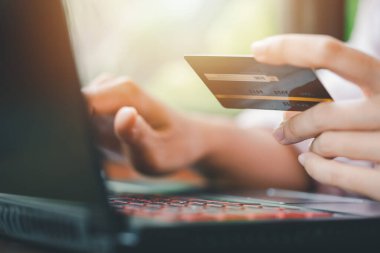 İnternetten alışveriş ve ödeme konseptini kullanarak kredi kartını tutan eller.