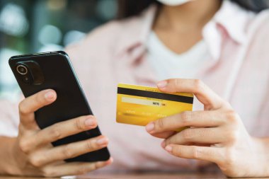 Akıllı telefon kullanarak online alışveriş ve ödeme konsepti kullanarak kredi kartı tutan eller