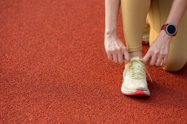 Sabahları spor ayakkabılarına ayakkabı bağlayan koşucu kadınların elleri yakındır.