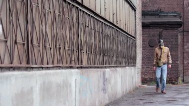 Gaz Maskeli adam tozlu fabrika duvar boyunca gider