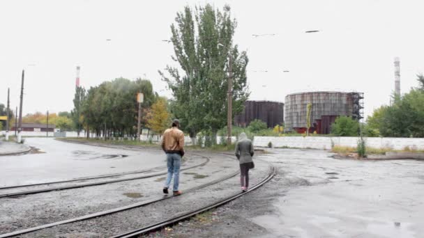 The guy with the girl in gas-helmets walk on rails — Stock Video