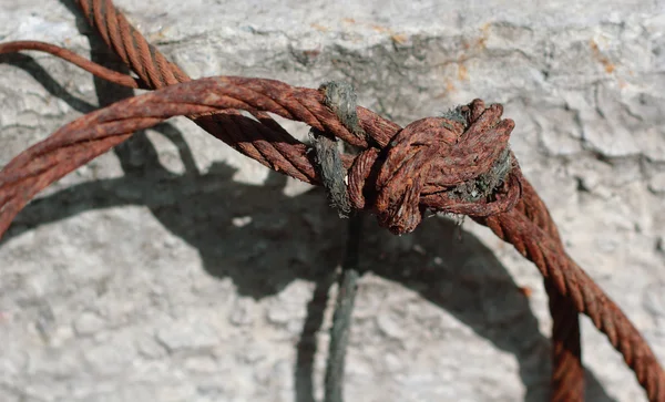 Knotted rusty steel wire against concrete wall — Stock Photo, Image