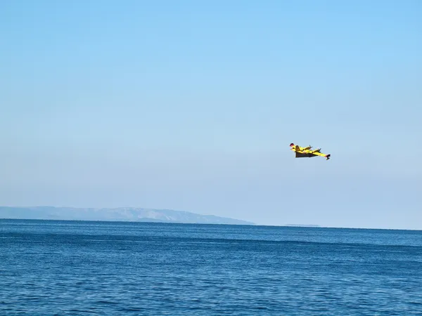 Airplane flying near blue sea — Stock Photo, Image