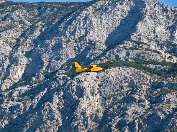 Avión amarillo volando cerca de la montaña — Foto de Stock