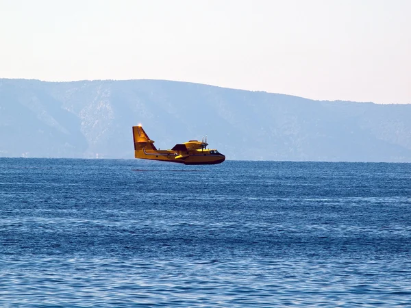 Yellow airplane flying near sea — Stock Photo, Image