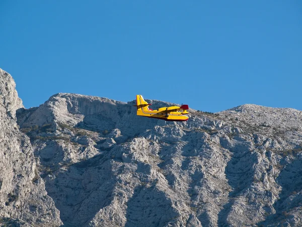 Пожарный самолет, летящий рядом с горой — стоковое фото