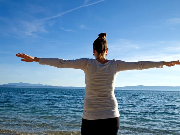 Junge Frau mit offenen Armen am Strand — Stockfoto