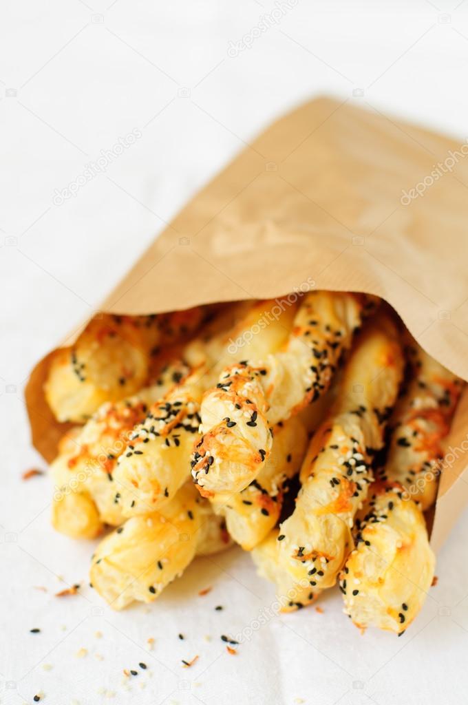 Puff pastry sticks with sesame seeds in a paper bag, copy space for your text