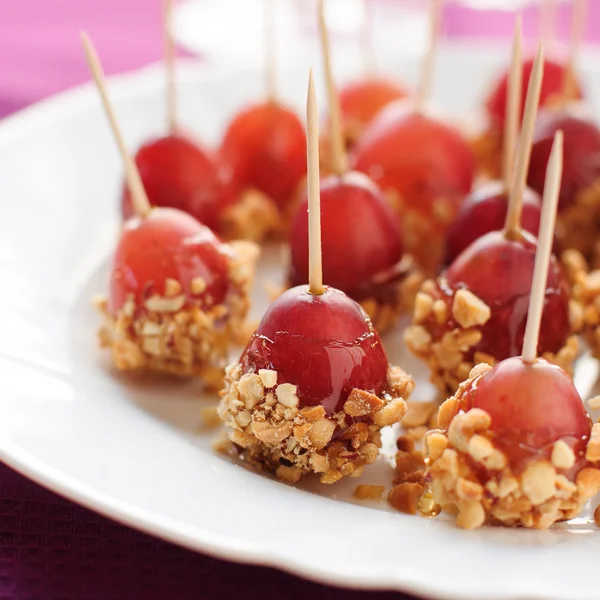 Caramel coated grapes with peanuts — Stock Photo, Image