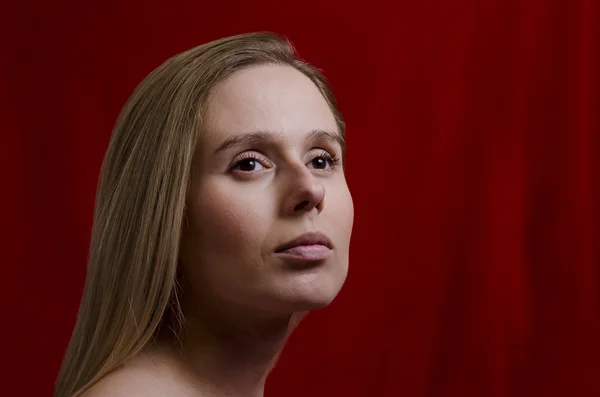 Porträt einer jungen Blondine auf rotem Hintergrund — Stockfoto