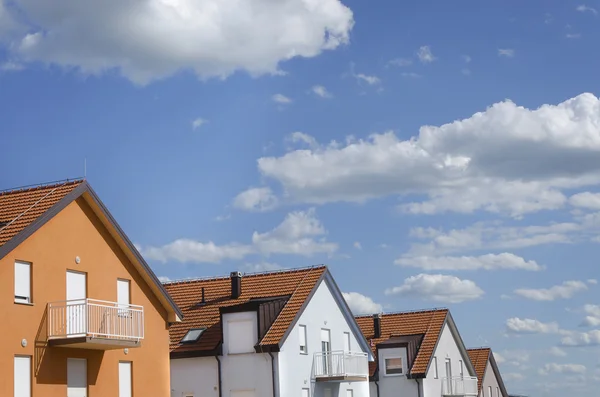 Roofs of houses under blue sky with clouds