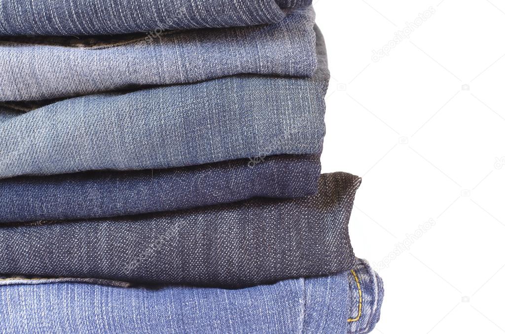 Close up stack of folded jeans on white background
