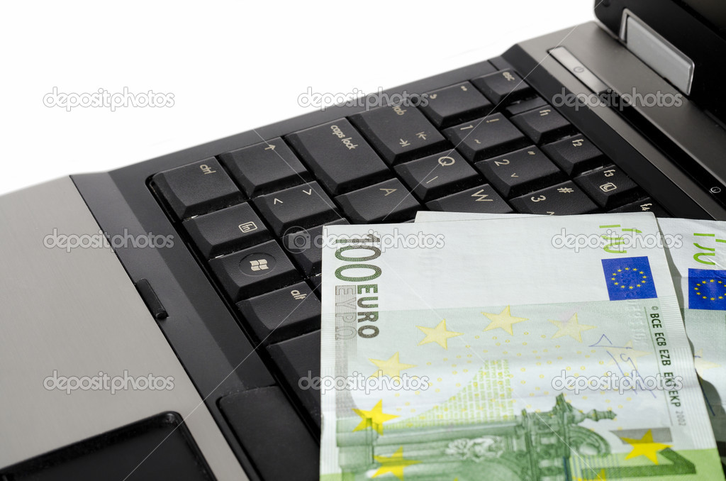 Close up of a laptop computer with couple of euro notes on the keyboard