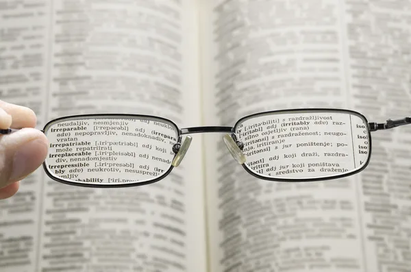 Vendo dicionário através de óculos — Fotografia de Stock