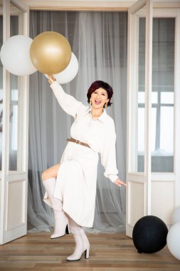 a girl with large balloons holds in one hand raising and bending her leg at the knees
