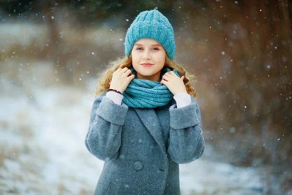a girl in a coat walks through a winter park