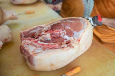 A slaughterhouse worker cuts chunks of meat into portions. A concept of sausage and delicatessen production.