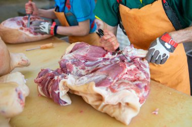 A slaughterhouse worker cuts chunks of meat into portions. A concept of sausage and delicatessen production.