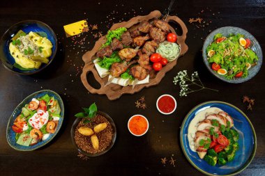 Barbecue on the grill. Mashed potatoes with pickles. Salad with quail eggs, pine nuts and tomatoes. Duck in bacon with broccoli, shrimp, salmon, caviar egg