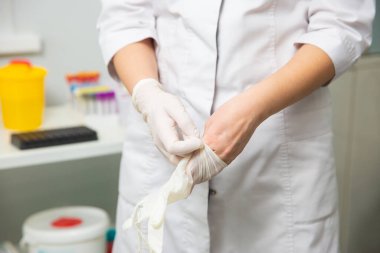 emale doctor puts on disposable gloves