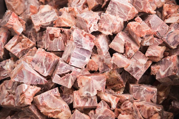 Frozen meat cut into cubes and slices and allowed to melt on the table. Display for sale in the supermarket. Production of meat semi- finished products.