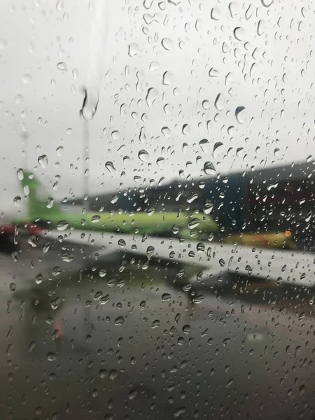 航空機の窓に雨の滴を通して 平面のぼやけた翼が見える — ストック写真