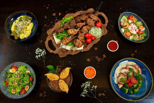 Barbecue on the grill. Mashed potatoes with pickles. Salad with quail eggs, pine nuts and tomatoes. Duck in bacon with broccoli, shrimp, salmon, caviar egg