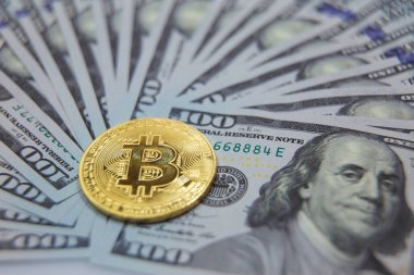 Dolar banknotlarının arka planına karşı Bitcoin. Bitcoin düşüşü