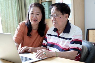 Evde dizüstü bilgisayar kullanan Asyalı çift..