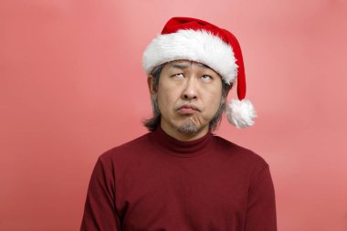 Pembe arka planda Noel Baba şapkalı Asyalı adam portresi..